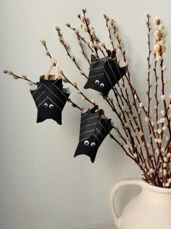Black DIY paper roll bats hanging on pussy willow in a vase