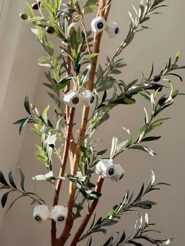 Egg carton eyeballs tied onto a faux olive tree for chic Halloween decor