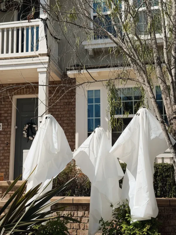 Front porch with DIY plastic tablecloth ghosts and black chiffon ribbon bows for Halloween