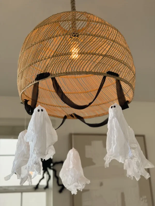 Tissue paper ghosts hanging from a rattan chandelier for Halloween